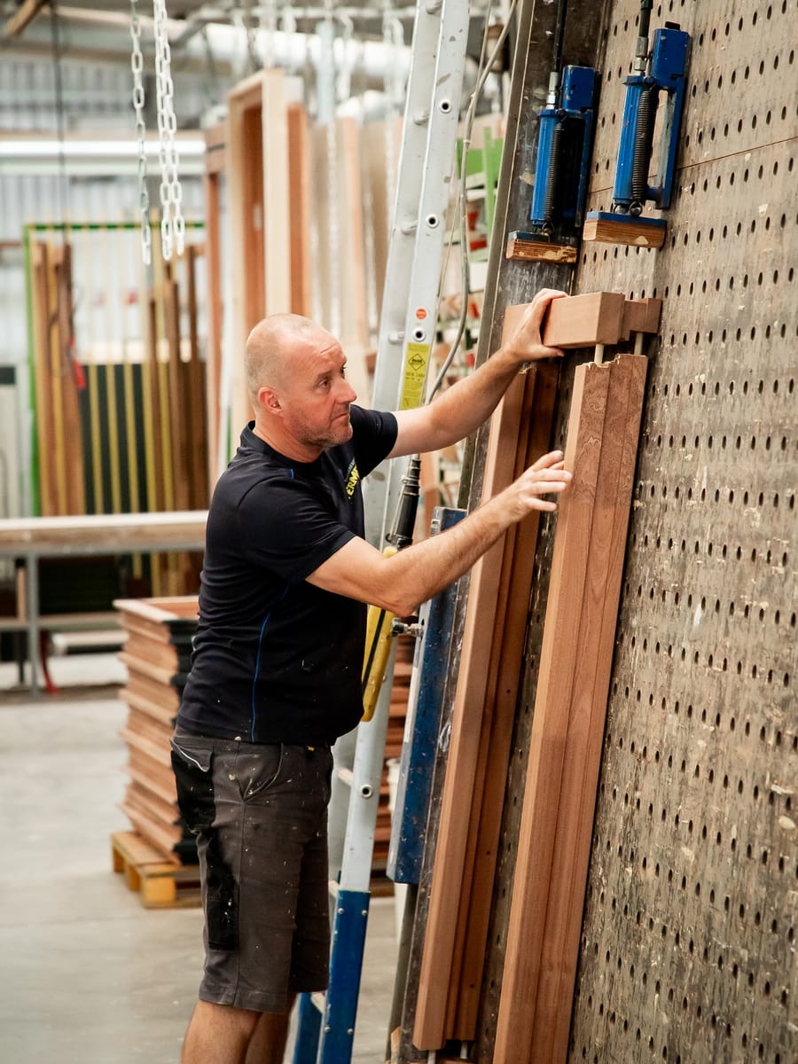 Medewerker zet een houten kozijn vast in de opsluitbank